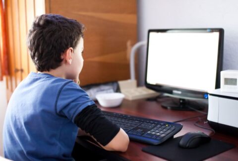 12406525 - selective focus indoor shot of a boy reading his computer's screen