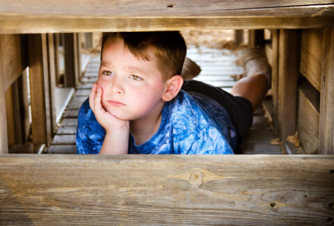 Unhappy child hiding and sulking while playing on playground