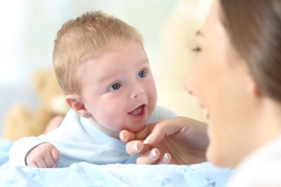 Close up portrait of a happy baby and mother looking each other on a bed